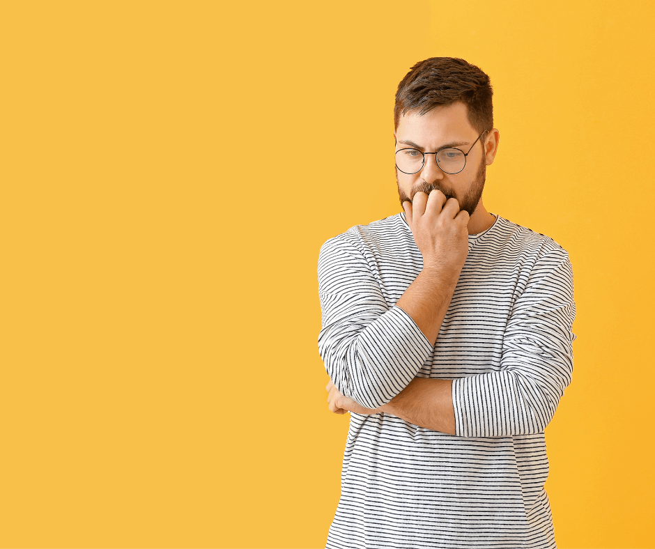 Man holding his hand up to his mouth looking down