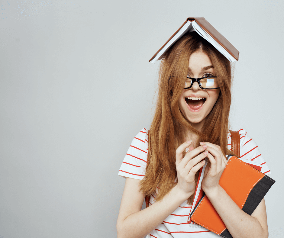 Woman standing smiling open mouthed with a open book on her head